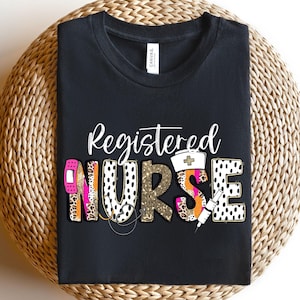 May include: Black t-shirt with the words "Registered Nurse" in a decorative font. The word "NURSE" features a bandage, leopard print, gold glitter, and a syringe design. A nurse's cap is also included in the design.
