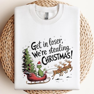 May include: White sweatshirt with a graphic featuring the Grinch in a sleigh, a Christmas tree, and reindeer. The text reads "Get in loser, We're stealing CHRISTMAS!"