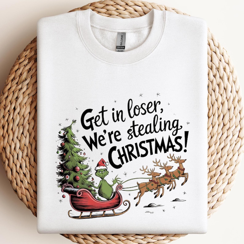 May include: White sweatshirt with a graphic featuring the Grinch in a sleigh, a Christmas tree, and reindeer. The text reads "Get in loser, We're stealing CHRISTMAS!"