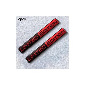 以下が含まれることがあります： 赤色の「LIMITED EDITION」という文字が入った黒色の長方形エンブレムが2つ。エンブレムは、質感のある白い表面に表示されています。「hand made」という文字が左上にあります。