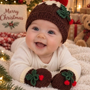 May include: A brown knit hat with a red pom-pom, a white top section, and green leaf and red berry accents, paired with matching brown knit mittens featuring white cuffs and identical green leaf and red berry embellishments.