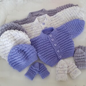 Puede incluir: Un conjunto de ropa de beb&eacute; de punto en color morado y blanco, que incluye un c&aacute;rdigan, dos gorros y dos pares de guantes.