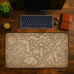 May include: A detailed, beige and brown map-themed desk mat with a black border. The mat features a fantasy map design, with a keyboard, monitor, coffee cup, and other items on a wooden desk. A small plant and a leather-bound notebook are also visible.