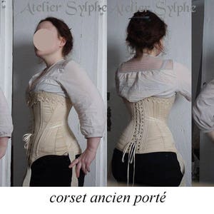 May include: A white cotton corset with a lace trim and a back lacing system. The corset is worn by a person and is shown from the front and back. The text "ref Z" and "corset ancien port&eacute;" is visible in the image.