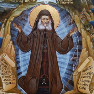 Pode incluir: Um ícone religioso representando um monge barbudo com hábito castanho e capuz, braços estendidos, segurando um terço. A figura está centrada contra uma luz azul radiante, rodeada por paisagens rochosas, pergaminhos com texto grego e figuras de Cristo e santos na parte superior.