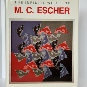 Może przedstawiać: Książka zatytułowana "THE INFINITE WORLD OF M. C. ESCHER" zawiera kolorową ilustrację ryb w czerwonym, czarnym, szarym i niebieskim kolorze. Książka ma białą okładkę z czerwonym tekstem.