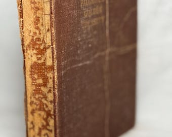May include: A vintage hardcover book with a brown cover and spine. The book's title, "PALMER'S GOLDEN UNIVERSITY", is printed in gold lettering. The spine shows signs of wear and tear, with the edges of the pages showing age.