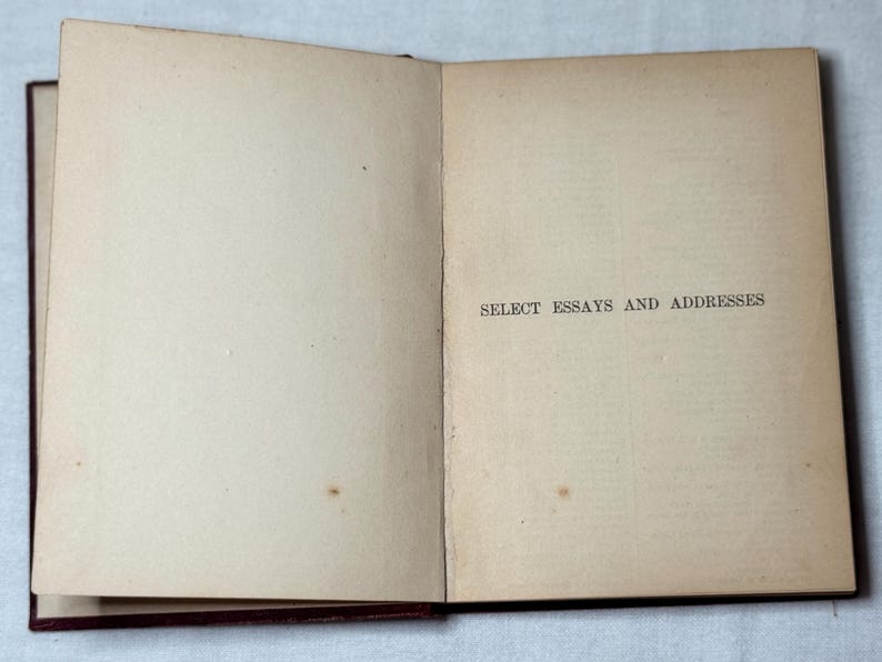 May include: An open book with cream-coloured pages. The right-hand page features the text "SELECT ESSAYS AND ADDRESSES" in black. The book has a dark red-brown binding. The pages show signs of age and use.