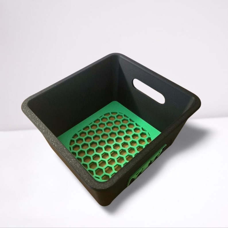 Puede incluir: Un contenedor de almacenamiento rectangular negro con un inserto verde con patr&oacute;n de panal. El contenedor tiene un exterior texturizado y un recorte de asa en un lado. El interior es verde con un dise&ntilde;o de panal.