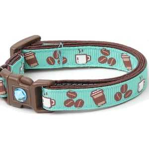Peut inclure: Un collier pour chat bleu turquoise avec une bordure brune et un motif de tasses à café et de grains de café. Le collier est doté d'une clochette.