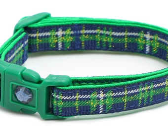 May include: A green and blue plaid cat collar with a blue bell. The collar has a plastic buckle.