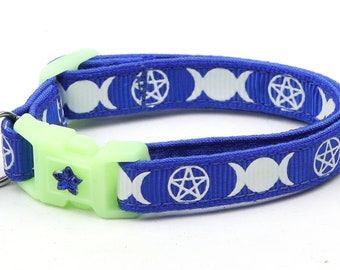 May include: A blue cat collar with a white triple moon and pentagram design. The collar has a glow-in-the-dark buckle and a blue bell.