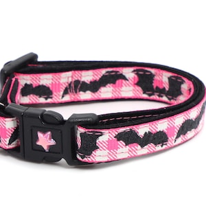 Puede incluir: Collar de gato de cuadros rosa y blanco con estampado de murci&eacute;lagos negros y una campanilla rosa.