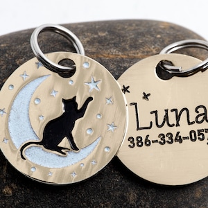 May include: Gold-toned pet ID tag with a black cat silhouette sitting on a crescent moon with stars. The other side of the tag has the name "Luna" and the phone number 386-334-0578.