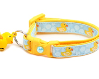 May include: A yellow and blue dog collar with a rubber ducky charm. The collar has a plastic buckle and a small bell. The collar is decorated with a pattern of rubber duckies and bubbles.