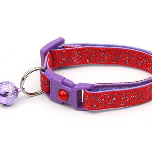 Puede incluir: Collar de gato rojo y morado con una campana. El collar está hecho de un material suave y cómodo y tiene una hebilla de seguridad.