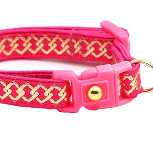 May include: Pink cat collar with a gold chain pattern and a pink and gold bell charm.