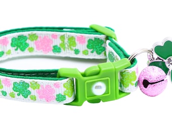 Könnte beinhalten: Ein grünes und weißes Halsband für Haustiere mit Kleeblatt-Muster und einem rosa Glöckchen-Anhänger mit einem Kleeblatt-Anhänger.