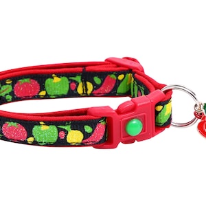 May include: Red and black cat collar with a bell shaped like a red pepper. The collar has a green button and a red buckle.