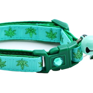 May include: A turquoise blue cat collar with a green glitter leaf pattern and a green leaf charm with a bell.