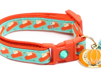 May include: A turquoise and orange cat collar with a pumpkin charm and a bell. The collar has a repeating pattern of pie slices with a white cat on top.