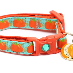 Op de afbeelding: Oranje en turquoise kattenhalsband met een pompoenontwerp en een gouden pompoenbedel met een bel.