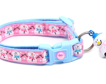 May include: A pink and blue adjustable dog collar with a snowman pattern and a snowman-shaped bell charm.
