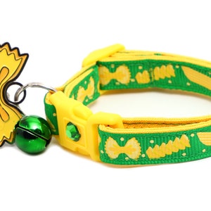 May include: A green and yellow cat collar with a yellow bowtie charm and a green bell. The collar has a yellow buckle and is decorated with a pattern of yellow pasta.