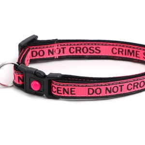 May include: Pink cat collar with a black "DO NOT CROSS CRIME SCENE" inscription and a pink bell.