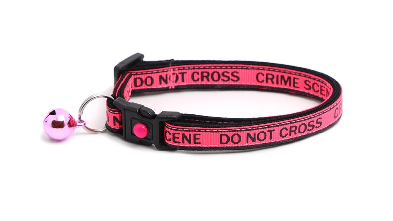 May include: Pink cat collar with a black "DO NOT CROSS CRIME SCENE" inscription and a pink bell.