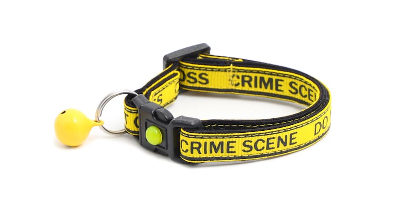 Op de afbeelding: Gele en zwarte hondenriem met de tekst "Crime Scene Do Not Cross" en een gele bel.
