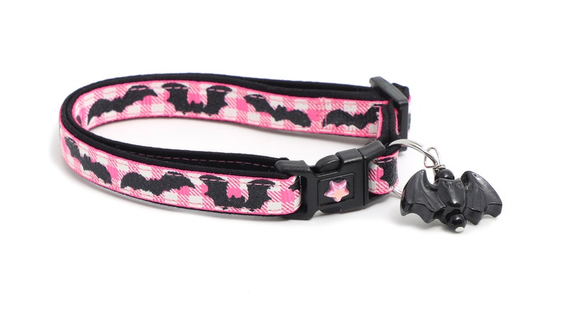 Puede incluir: Collar de gato rosa y negro con un dije de murci&eacute;lago negro. El collar tiene una hebilla negra y una estrella rosa en la hebilla. El collar est&aacute; hecho de un material suave y c&oacute;modo.