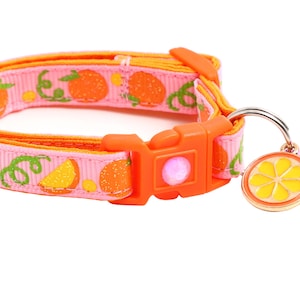May include: A pink and orange cat collar with a citrus fruit print and a small bell charm. The collar has an adjustable buckle.