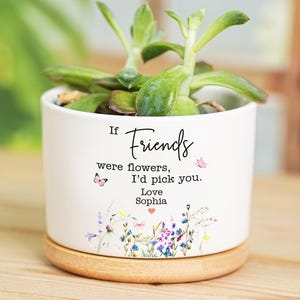 May include: A white ceramic plant pot with a succulent. The pot has a wooden base and the text "If Friends were flowers, I'd pick you. Love Sophia" with floral and butterfly details.