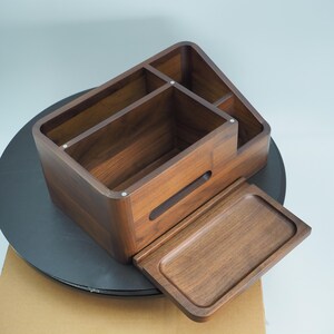 May include: A wooden desk organizer with multiple compartments and a pull-out tray. The organizer is made of dark brown wood and has a smooth finish. The compartments are of varying sizes and shapes, suitable for storing office supplies.