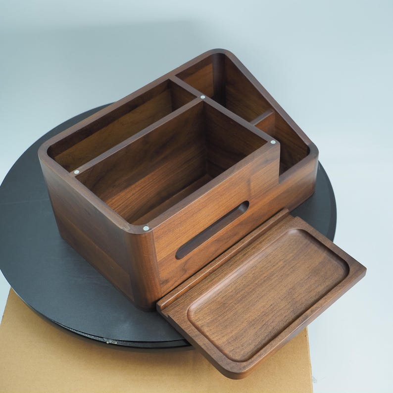 May include: A wooden desk organizer with multiple compartments and a pull-out tray. The organizer is made of dark brown wood and has a smooth finish. The compartments are of varying sizes and shapes, suitable for storing office supplies.
