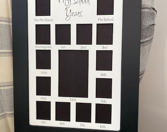 May include: Black picture frame with white matting and cutouts for photos. The frame has the text "My School Years" and labels for each grade from Pre-Pre School to 12th grade.
