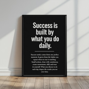 May include: A black rectangular wall art print featuring white text that reads: Success is built by what you do daily. Below this, smaller white text reads: Success rarely comes from one perfect moment. It grows from the habits you repeat.