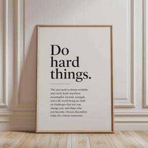 May include: A framed wall art print featuring the black text Do hard things. followed by a horizontal line and a paragraph of motivational text that reads: The easy path is always available and rarely leads anywhere meaningful. Growth, strength, and a life worth living are built on challenges that test you, change you, and shape who you become. Choose discomfort today for a better tomorrow.