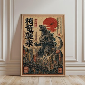 May include: A framed vintage-style poster featuring Godzilla in a city setting. The artwork uses a red, black, and beige color palette, with Japanese text and a large red sun in the background. The poster is displayed on a wooden floor.