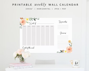 Może przedstawiać: Drukowany cotygodniowy kalendarz ścienny w formacie poziomym, o wymiarach 61 cm x 91 cm. Kalendarz zawiera wzór kwiatowy z różowymi i żółtymi kwiatami, a także sekcje: "Tydzień", "Najważniejsze priorytety", "Zakupy" i "Cytat tygodnia".
