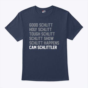 May include: Navy blue t-shirt with the phrases "GOOD SCHLITT, HOLY SCHLITT, TOUGH SCHLITT, SCHLITT SHOW, SCHLITT HAPPENS, CAM SCHLITTLER" printed in a gray and white font. The shirt has short sleeves and a crew neck.