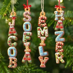 May include: Gingerbread cookie ornaments spelling out names: Jacob, Sofia, Emily, and Hanzer. Each letter is decorated with colorful icing and festive designs, hanging from a Christmas tree.