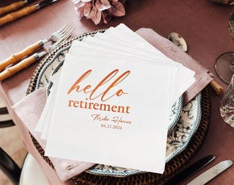 May include: A stack of white paper napkins with the words "hello retirement" printed in copper-colored script. The napkins are on a decorative plate with a floral design, set on a pink tablecloth. The date 04.21.2024 is printed below the name Mike Harris.