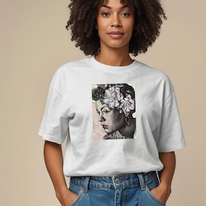 May include: White t-shirt with a graphic print of a woman's portrait. The portrait is in black and white with floral accents. The model is wearing blue jeans.