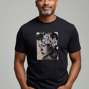 May include: Black t-shirt featuring a portrait of a woman with flowers in her hair. The portrait is in black and white with a map background. The t-shirt is worn by a person with gray hair and a beard.
