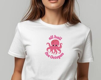 May include: White t-shirt featuring a pink octopus graphic with the text "all hail the Octopus". The octopus has eight tentacles and is centered on the shirt. The shirt is being worn by a person.