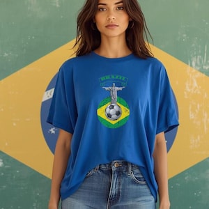 May include: A blue t-shirt featuring a graphic of Christ the Redeemer, a soccer ball, and the word "BRAZIL" in green. The shirt is paired with denim shorts. The background is a Brazilian flag.