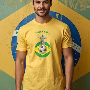May include: Yellow t-shirt featuring a graphic of Christ the Redeemer statue, a soccer ball, and the word "BRAZIL" on a banner. The design is set against a Brazilian flag background. The shirt is short-sleeved.