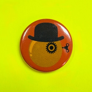 Könnte beinhalten: Ein runder Button mit orangefarbenem Hintergrund und einem Design mit schwarzem Bowlerhut. Der Button zeigt ein Zahnrad und einen Aufziehschlüssel, vor gelbem Hintergrund.